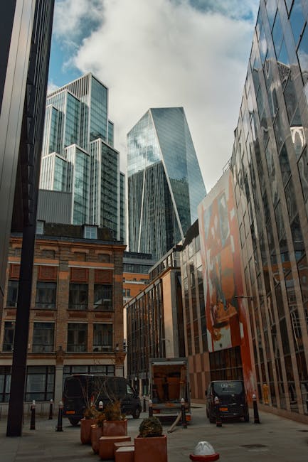 An upward view between two closely situated buildings on Shoreditch High Street, showing a narrow passageway with a black metal fire escape staircase attached to the brick wall on the left side. The b